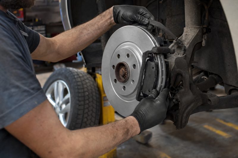 Technician replacing a brake rotor and pads